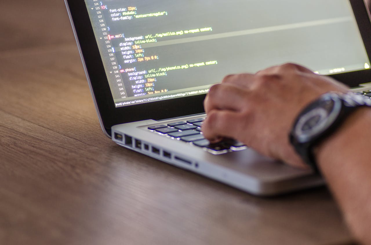 A close-up shot of a person coding on a laptop, focusing on the hands and screen.